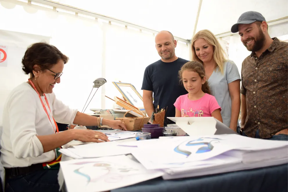 Zohra creating a live calligraphy in front of a family at an event