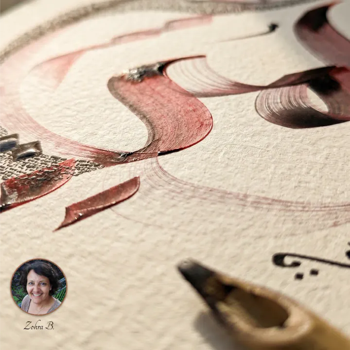 Close-up of Zohra's calligraphy in progress, with ink still glistening and a calame resting on the paper